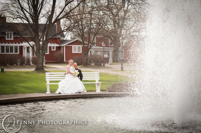 bride and groom sitting on bench by fountain at the Earle Brown Event Center MN